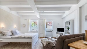 Un dormitorio moderno con cama, sofá, televisor y estantería.