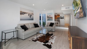 A modern living room with a sofa, coffee table, and a large TV mounted on the wall.