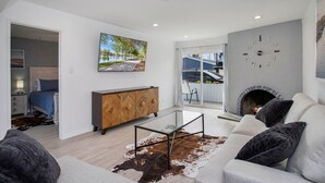 A modern living room with a glass coffee table, a fireplace, and a sofa.