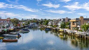 A marina with boats docked, waterfront buildings, and a clear sky.