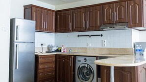 A modern kitchen with stainless steel appliances, wooden cabinets, and a tiled backsplash.
