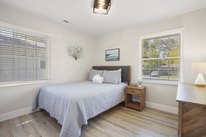 A bedroom with a bed, bedside table, lamp, and a painting on the wall.
