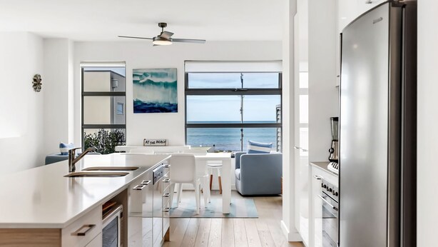 A modern kitchen with a large island, a dining area, and a view of the ocean. - Stunning Sea Views in Excellent Location (Victor Harbor)