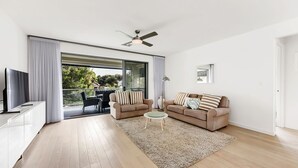 A modern living room with two sofas, a coffee table, a TV, and a sliding glass door leading to an outdoor area. - Stunning Sea Views in Excellent Location (Victor Harbor)