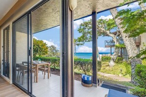 A modern villa with a glass-enclosed balcony overlooking a beach and ocean.