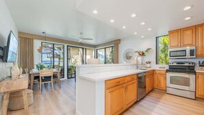 Une cuisine moderne avec des meubles en bois, un grand îlot central et des appareils électroménagers en acier inoxydable.