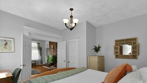A bedroom with a bed, a desk, a chair, a dresser, a mirror, and a chandelier. - Modern Boho🪴Style 1BR Near DT on Historic Street (Columbus)