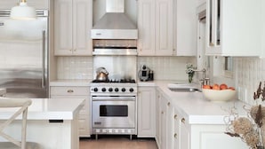 Une cuisine moderne avec des meubles blancs, des appareils en acier inoxydable et un îlot central en bois.