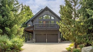 Une maison à deux étages avec un balcon, deux portes de garage et une allée.