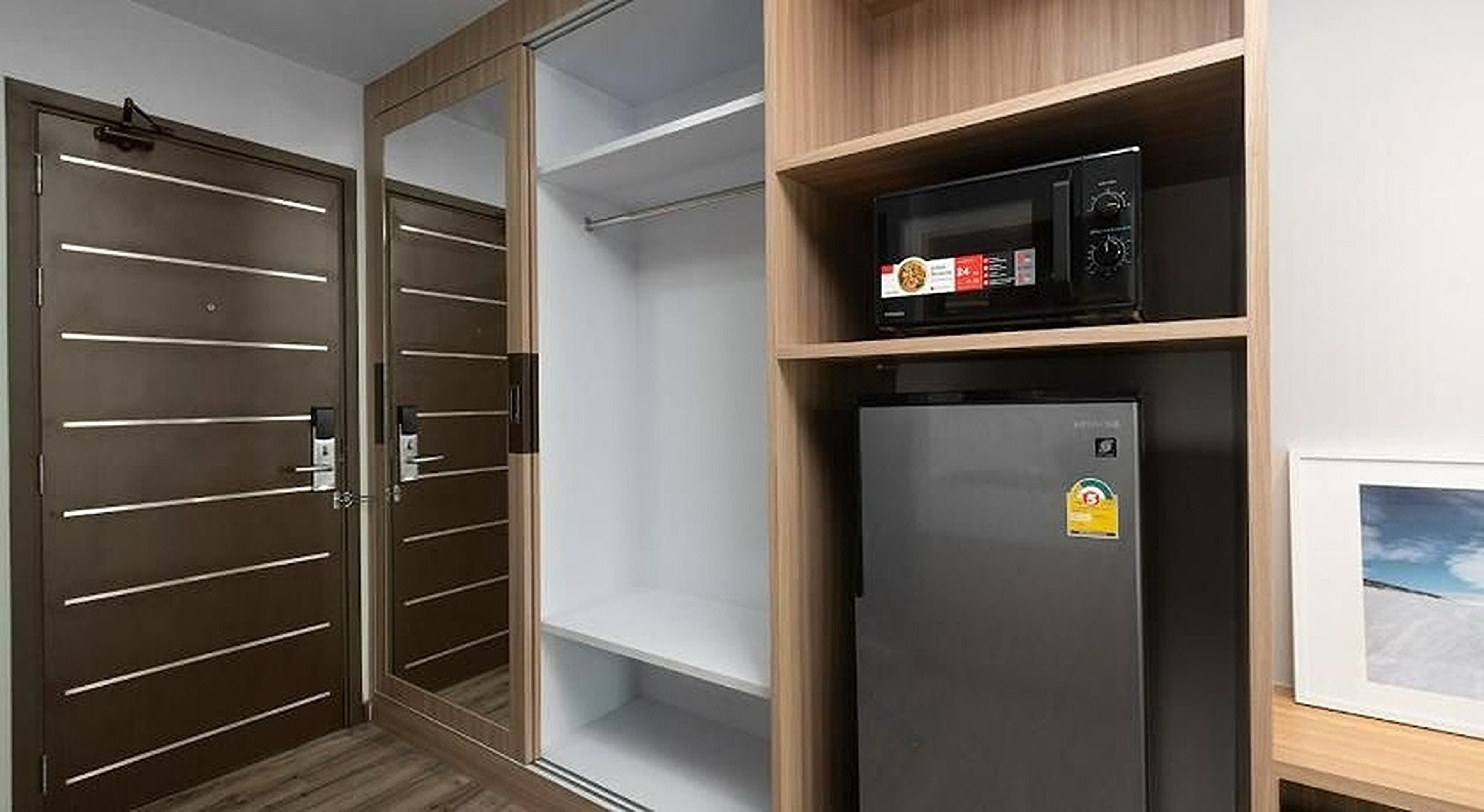 A room with a wardrobe, a microwave, and a refrigerator.