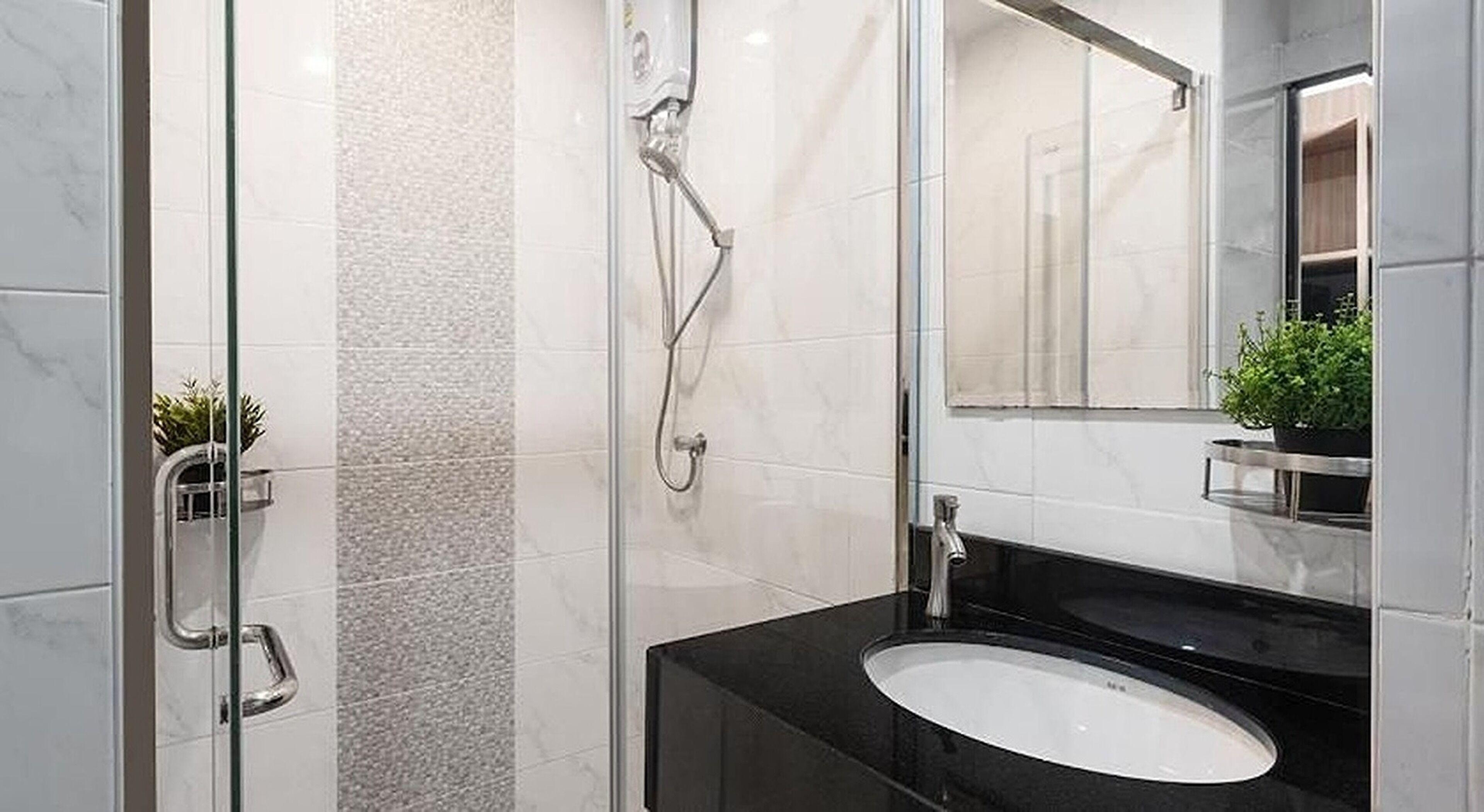 Une salle de bain moderne avec une douche à parois de verre, un lavabo sur un plan de toilette noir et un miroir au-dessus.
