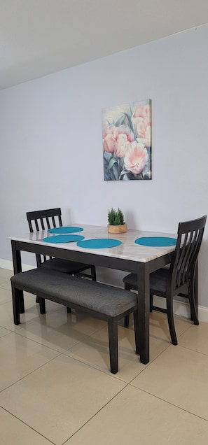 A dining table with a bench, two chairs, and a potted plant.