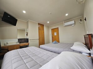 A hotel room with two beds, a TV, a mirror, a wooden wardrobe, and a small desk with a sink. - White Horse Inn Restaurant & Motel (Longburn)