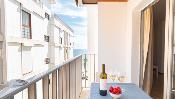 Ein Balkon mit Tisch für zwei Personen, einer Weinflasche und einer Schale Erdbeeren.