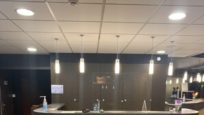 A reception desk with a wooden finish, a digital screen, and a hand sanitizer dispenser. - Hostellerie Saint-Vincent (Nuits-Saint-Georges)