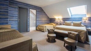 A modern bedroom with a sloped ceiling, a large bed, two bedside tables with lamps, and a small seating area with chairs. - Hostellerie Saint-Vincent (Nuits-Saint-Georges)