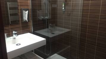 A modern bathroom with a glass-enclosed shower, a white sink, and a built-in toilet.