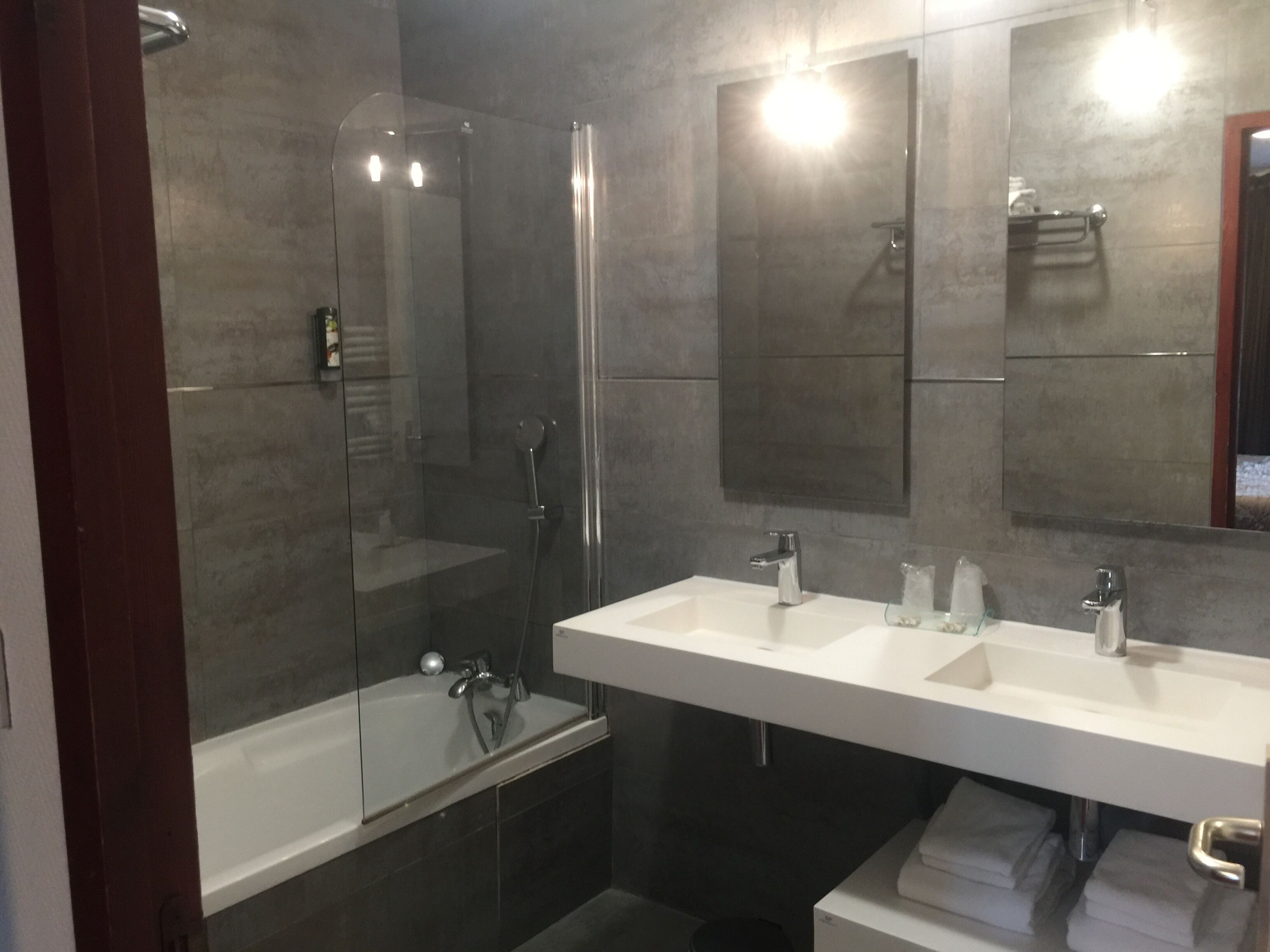 A modern bathroom with a glass-enclosed shower, a double sink vanity, and a large mirror.