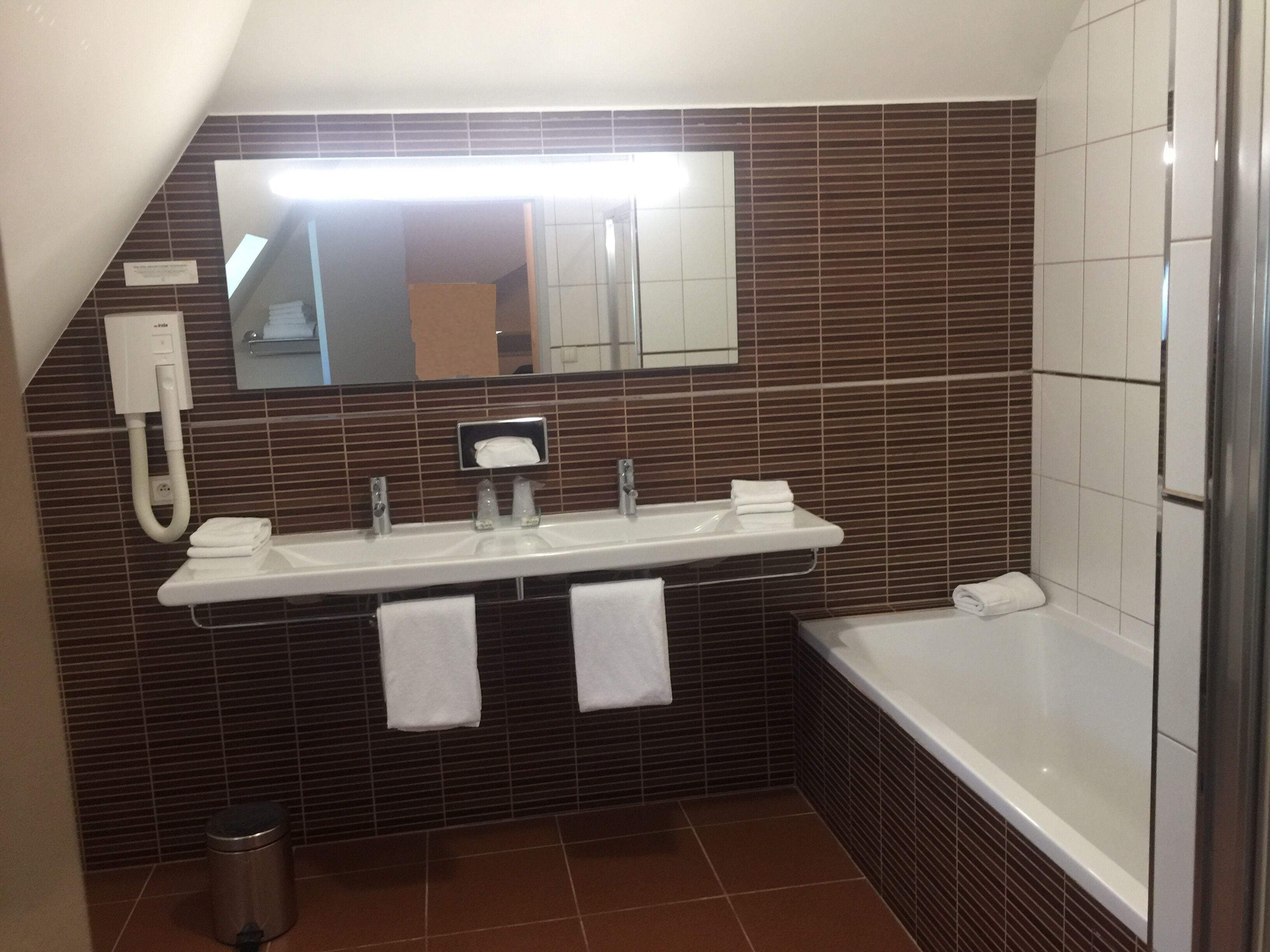 A modern bathroom with a long sink, a mirror, and a bathtub.
