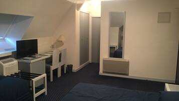Habitación de hotel con cama, escritorio con computadora, televisor, espejo y armario.