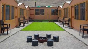 Filas de habitaciones con un espacio verde central y una fogata.