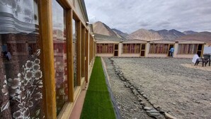 Un pasillo con césped artificial verde que conduce a una fila de habitaciones con vistas a montañas.