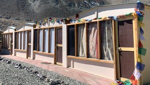 Una hilera de edificios sencillos de una sola planta con ventanas grandes, presumiblemente habitaciones de huéspedes, en una zona montañosa con cielo despejado.