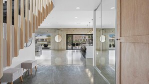 Un interior moderno con escaleras, zona de estar y ventanas amplias.
