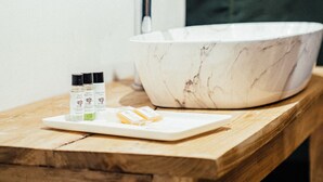 Un baño con lavamanos de mármol, un espejo y encimera de madera.