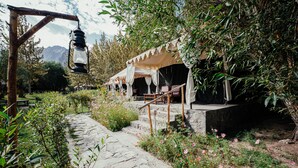 Un entorno rústico al aire libre con un sendero de piedra que lleva a varias tiendas de campaña con toldos blancos.