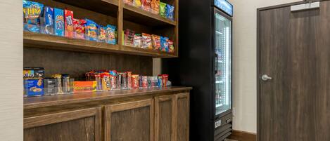 Un mostrador de bar con diferentes snacks empaquetados y un refrigerador.