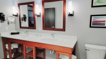 A bathroom with a double sink vanity, two mirrors, a toilet, and a framed map on the wall.