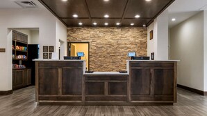 A reception area with a stone wall, wooden reception desk, and a snack bar. - Comfort Suites Paducah Mall Area (Paducah)