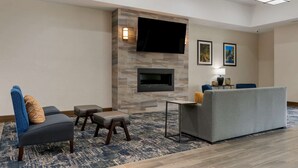 A modern living room with a stone fireplace, a flat-screen TV, and a grey sofa. - Comfort Suites Paducah Mall Area (Paducah)