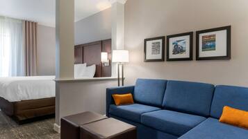 Una habitación de hotel con una cama, un sofá azul, una mesita y cuadros en la pared.