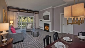 Una sala de estar moderna con chimenea, un sofá, una mesa de comedor y un televisor sobre la chimenea.