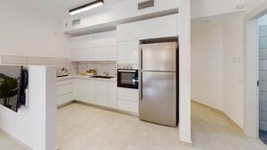 Een moderne keuken met witte kasten, een roestvrijstalen koelkast, een inbouwoven en een spoelbak.