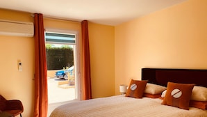 Ein Hotelzimmer mit einem großen Bett, einem Sessel, einem Schreibtisch und Blick ins Freie.