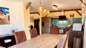 Eine moderne Küche mit einer großen Kochinsel, Edelstahlgeräten und einem Essbereich mit Holztisch und Ledersesseln.