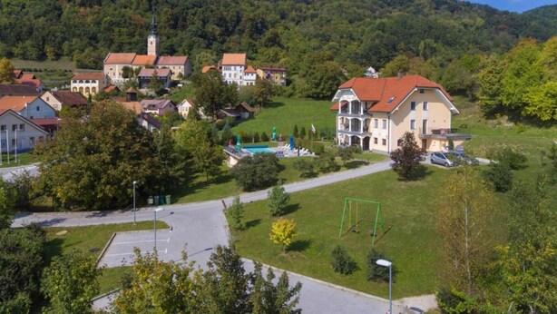 A village with traditional architecture, a church, and a swimming pool.