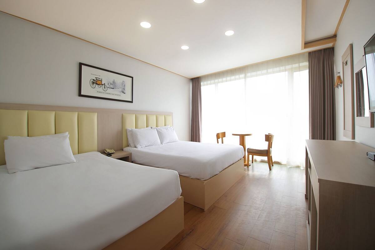 A hotel room with two beds, a desk, and a chair.