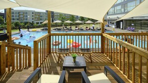 A poolside area with wooden deck, lounge chairs, and umbrellas.