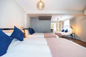 A hotel room with three beds, a wooden accent wall, and a large mirror reflecting the room.
