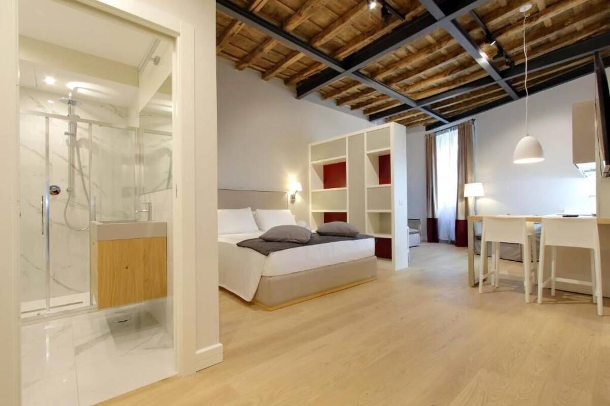A modern bedroom with a wooden ceiling, a bed, a desk, and built-in shelving.