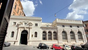 A historic building with a large arched entrance, multiple windows, and parked cars in front. - Monti Panisperna Suites (Rome)