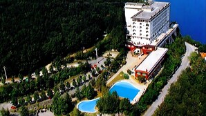 Vista aérea de un hotel con varias construcciones, una piscina y una carretera que conduce al establecimiento.
