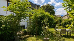 Une cour avec un bâtiment blanc, une tour ronde et diverses plantes en pot.