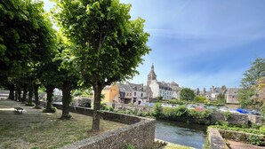 Un sentier pavé de pierres, un mur de pierre et une rivière traversée par un pont.