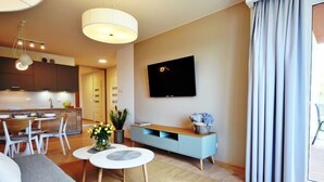 Una sala de estar moderna con un sofá, una mesa de centro, un televisor y un comedor con sillas y una mesa.