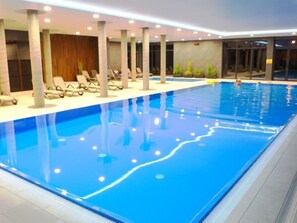 An indoor swimming pool with lounge chairs and a wooden wall.